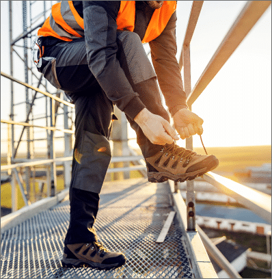 Homme laçant ses chaussures de sécurité sur un chantier